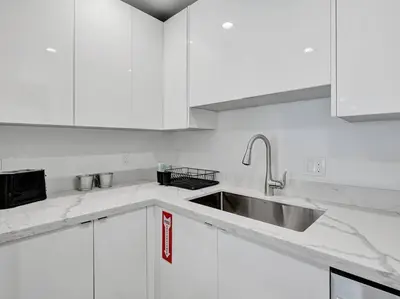 a white kitchen with a sink and white cabinets at Contemporary 2BR Home with Pool & BBQ Access in Fort Lauderdale