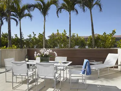 a patio with white chairs and tables and palm trees at Grand Beach Hotel Surfside West in Miami Beach
