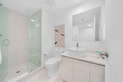 a white bathroom with a toilet and a glass shower at Beachwalk 2 Bedrooms with Kitchen 2 Bathroom & Gym in Hallandale Beach
