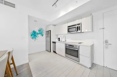 a kitchen with white cabinets and a stove top oven at Beachwalk -1 Bedroom With Kitchen Pool And Gym in Hallandale Beach