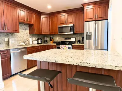 a kitchen with wooden cabinets and a granite counter top at Spacious 4/4 Home Central To All Attractions in Hollywood
