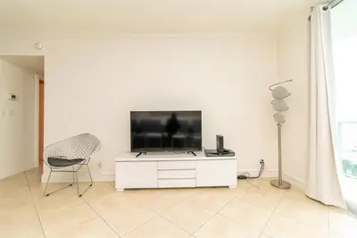 a white living room with a tv and a chair at PROMO Komffy Home with King Bed & Ocean View at Tides 7th floor in Hollywood