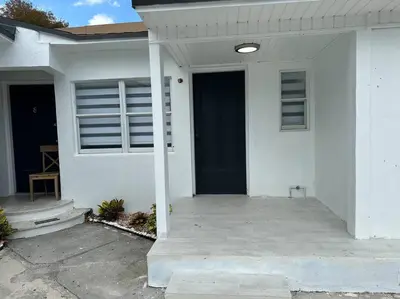 a white house with a front porch with a blue door at VillaClara Studio-Little Havana in Miami