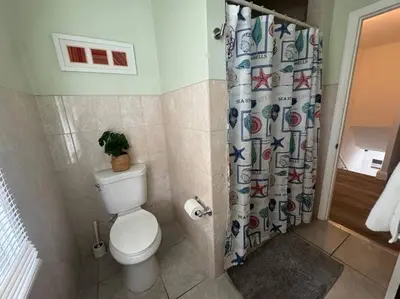 a bathroom with a toilet and a shower curtain at Brickell + Wynwood Wonderland: Spacious 6BR Home in Miami