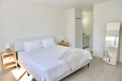 a bedroom with a large white bed and a mirror at 1BR with Kitchen Close To Sunny Isles Beach in North Miami Beach
