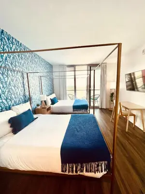 a bedroom with two beds with blue walls and a table at 2BR-2BA Oasis W-Stunning Views at Beachwalk in Hallandale Beach