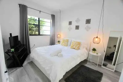 a bedroom with a white bed and a window at CHIC AND MODERN APARTMENT STEPS FROM THE BEACH in Miami Beach