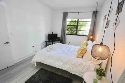 a white bedroom with a bed and a window at CHIC AND MODERN APARTMENT STEPS FROM THE BEACH in Miami Beach