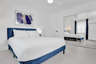 a white bedroom with a large bed and a mirror at Hallandale Beach Modern apartment Chic Backyard in Hallandale Beach