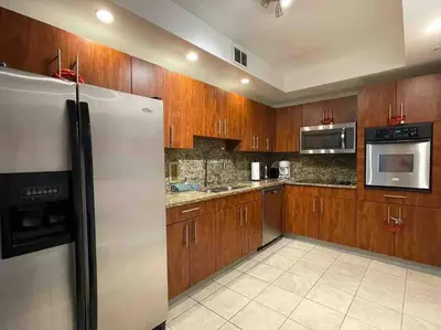 a kitchen with wooden cabinets and a stainless steel refrigerator at Ocean view 1 bedroom in Hollywood in Hollywood
