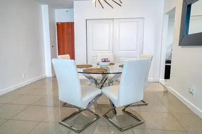 a dining room with a glass table and white chairs at Amazing apartment by the Ocean in Hollywood