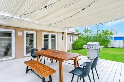 a patio with a wooden table and chairs and a grill at Walk to Beach Luxury 5BR & 3BA Villa Hollywood Lakes in Hollywood