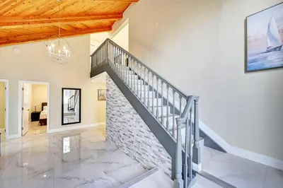 a staircase in a living room with a brick wall at Luxury 5BR & 3BA Villa Walk to Hollywood Beach in Hollywood