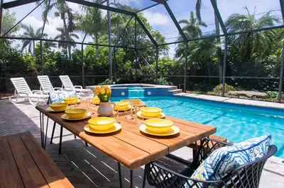 a wooden table with yellow dishes on it next to a pool at Fabulous 5BR & 3BA Villa near Hollywood Beach in Hollywood