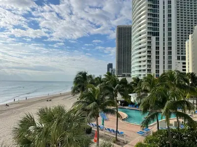 a view of a beach with palm trees and a building at Lovely 2 bedroom with side ocean view in Hollywood