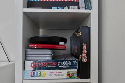 a book shelf with a stack of games and books at Modern Tropical Pool House North Miami Hot Tub in Miami