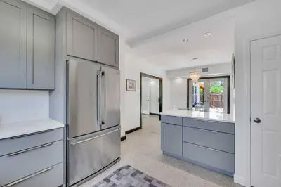 a kitchen with white cabinets and a stainless steel refrigerator at Modern Tropical Pool House North Miami Hot Tub in Miami