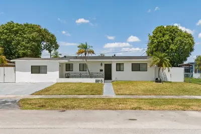 a white house with palm trees in front of it at Miami Oasis, Spacious 4-Bedroom Home with Pool in Miami