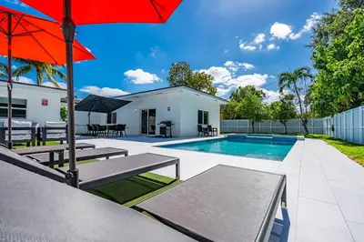 a swimming pool with a red umbrella and a house at Stylish 4 Bedroom Home with Pool, 12 Minutes to the beach in Miami