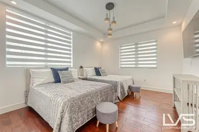 a bedroom with two beds and two windows at Victoria Villa - Walk to Las Olas - 4 Bed 4 Bath in Fort Lauderdale