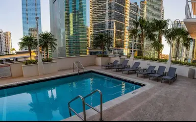 a pool on the roof of a building with chairs and palm trees at Sublime 1 BED 1 BTH • Brickell BAY & CITY VIEW in Miami