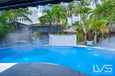 a swimming pool with a fountain in front of a house at Floridita 5Bed 4Bath FTL Paradise with Tiki Hut Heated Pool in Fort Lauderdale