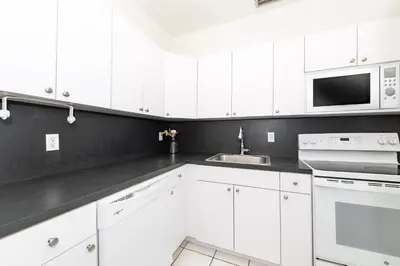 a white kitchen with white cabinets and a microwave at Art Deco Washingthon Apartment in Miami Beach