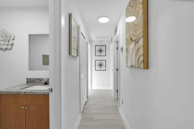 a hallway of a bathroom with a sink and a mirror at Chic Miami Private Pool Home in Cutler Ridge