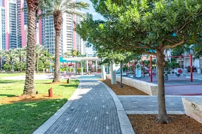 a walkway in a park with palm trees and buildings at Cozy newly furnished apartment , on the 6th floor. in Sunny Isles Beach