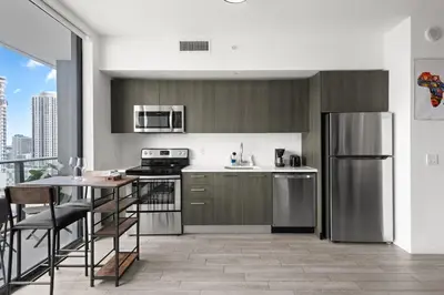 a kitchen with stainless steel appliances and a table at Breezy Stays Luxury Residences - near Kaseya Center in Miami