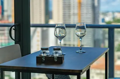 two wine glasses sitting on a table on a balcony at Breezy Stays Luxury Residences - near Kaseya Center in Miami