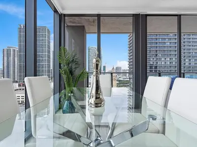 a glass dining room table with white chairs and a window at X Lounge IV-Skyline Corner Residence in Miami