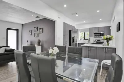 a dining room and kitchen with a glass table and chairs at Casa Coral with Pool Charcoal BBQ area in Miami