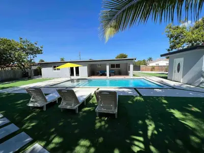 a swimming pool with chairs and a house at Renovated Grand Villa Paradise Amazing pool, BBQ & Ping Pong in Tamiami