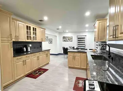a large kitchen with wooden cabinets and a sink at Renovated Grand Villa Paradise Amazing pool, BBQ & Ping Pong in Tamiami
