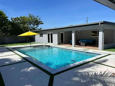 a swimming pool with a yellow umbrella next to a house at Miami dream resort heated pool sleeps 8 in Tamiami