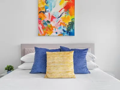 a painting hangs above a bed with blue pillows at X Lounge-Contemporary Corner Residence in Miami