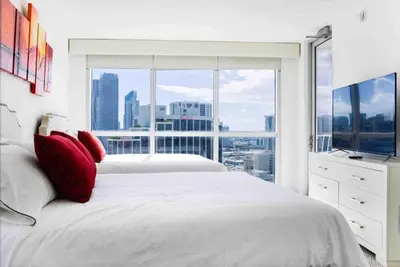 a white bedroom with a large window and a bed with red pillows at Beautiful apartment Miami, FL in Miami