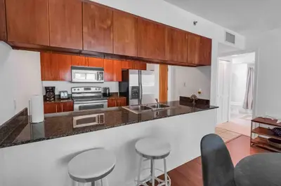 a kitchen with wooden cabinets and bar stools at Bay View 1 BDR 1 BTH • Brickell • Free Parking in Miami