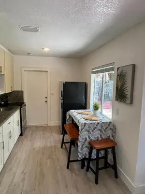 a kitchen with a table and a black refrigerator at House 2 Bedrooms plus CouchBed Best Location MIami Private Parking, Laundry, Storage for Luggage in Miami