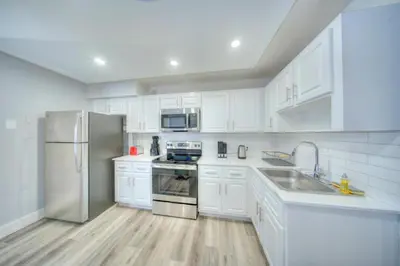 a kitchen with white cabinets and a stainless steel refrigerator at Mahalo Isles Apartments by Rocketstay in Fort Lauderdale