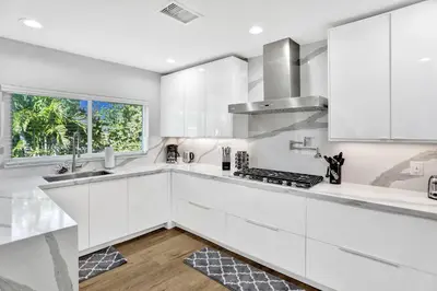 a white kitchen with white cabinets and a window at Modern home w heated pool canal views in Hollywood