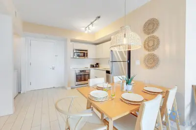 a kitchen and dining room with a wooden table and chairs at Beachwalk Resort Prime Location Balcony Gym in Hallandale Beach