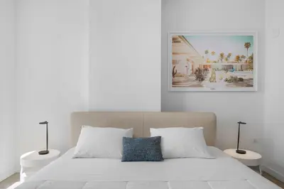 a white bedroom with a bed with two night stands at High Style Living in the Heart of Miami in Miami