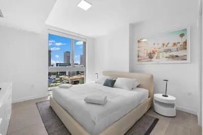 a white bedroom with a large bed and a large window at High Style Living in the Heart of Miami in Miami