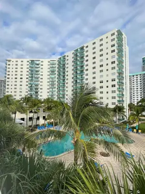 a large building with a palm tree next to a beach at Tropical ocean view 1 bedroom in Hollywood