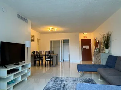 a living room with a couch and a tv and a table at Ocean front 1 bedroom in Tropical Paradise in Hollywood
