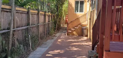 a sidewalk next to a fence next to a house at Cosy new studio with yard space in Miami in Miami