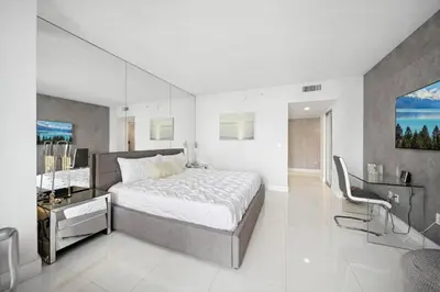 a bedroom with a large bed and a mirror at Million Dollar Waterfront Penthouse in Hallandale Beach