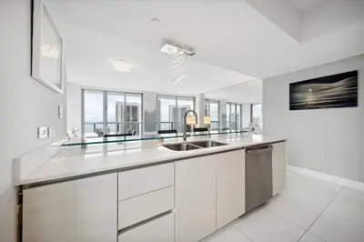 a white kitchen with a sink and some windows at Million Dollar Waterfront Penthouse in Hallandale Beach